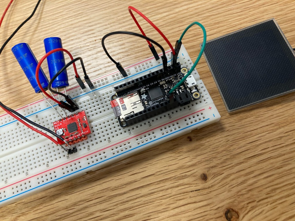 My solar-powered poetry setup: PCBs on a breadboard, with a nearby small solar panel