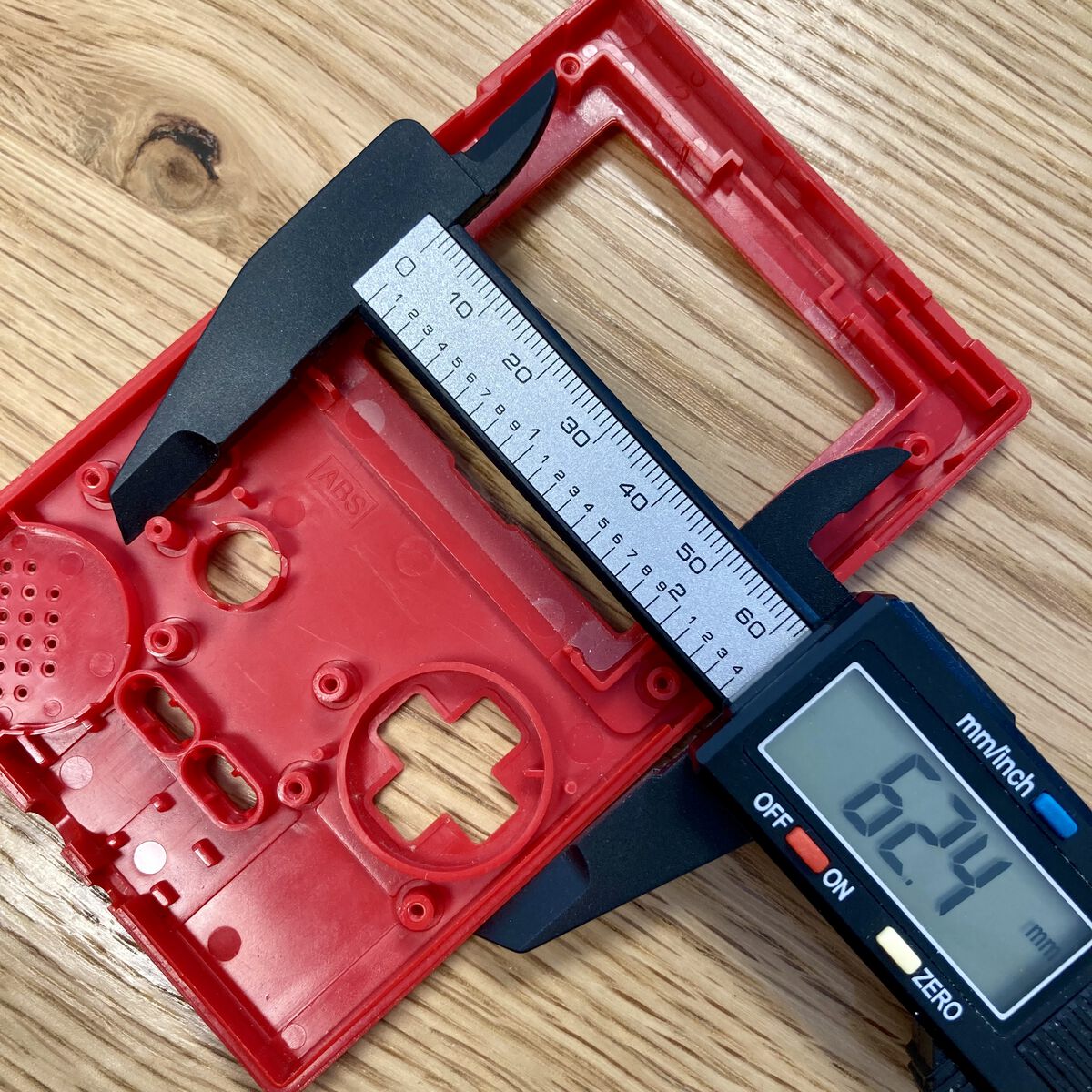 Digital calipers measuring distance between components on the upper inside of a Game Boy Pocket shell